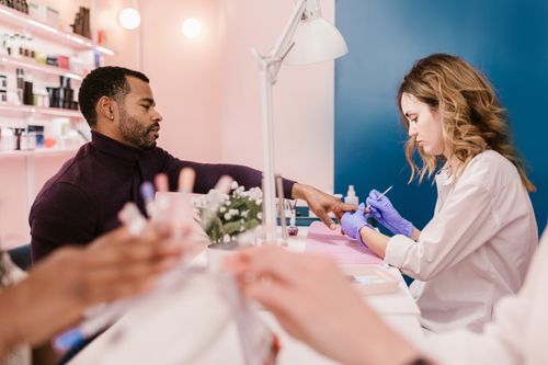 Free A man receives a manicure from a nail technician in a stylish, modern salon setting. Stock Photo