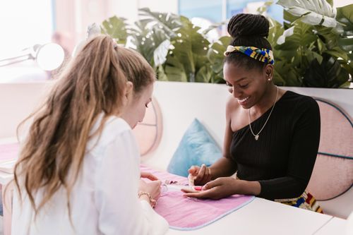 Free Two women enjoying a manicure session in a bright nail salon setting. Stock Photo