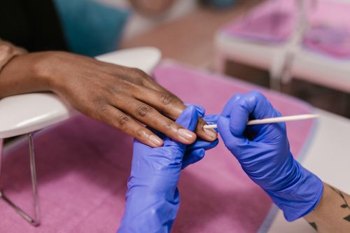 Free Close-up of a manicure session with blue latex gloves in a salon setting. Stock Photo