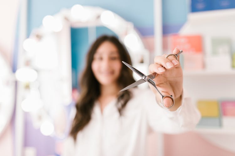 Woman In White Long Sleeves Holding A Silver Scissors 