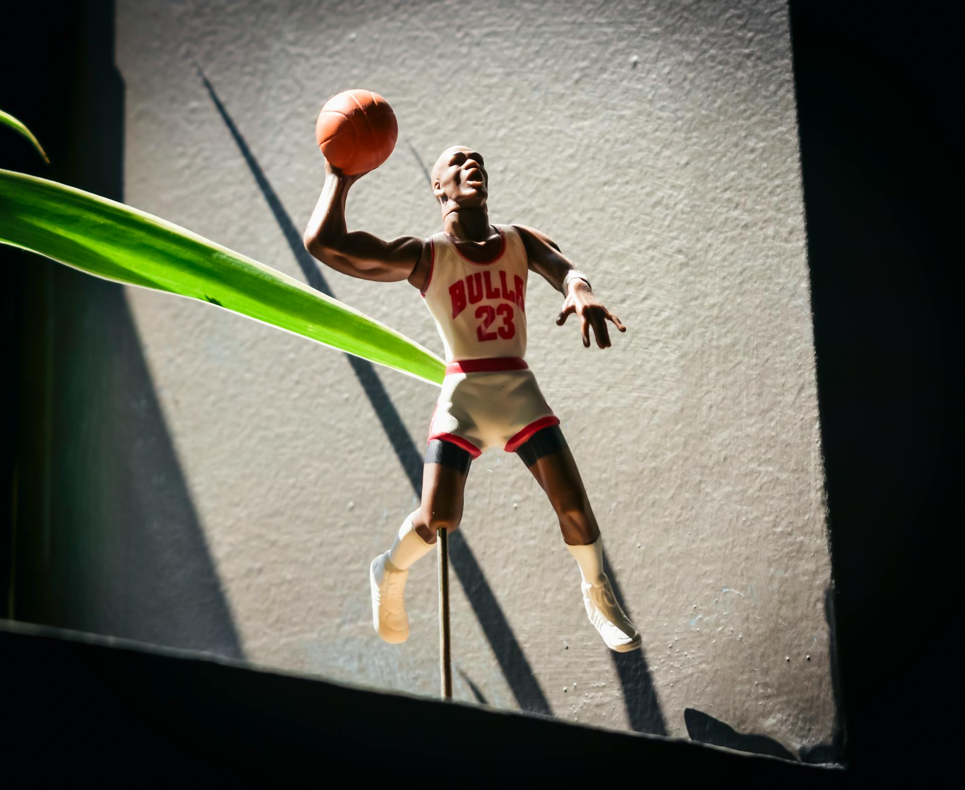 A Michael Jordan Figurine in White and Red Uniform Holding a Ball