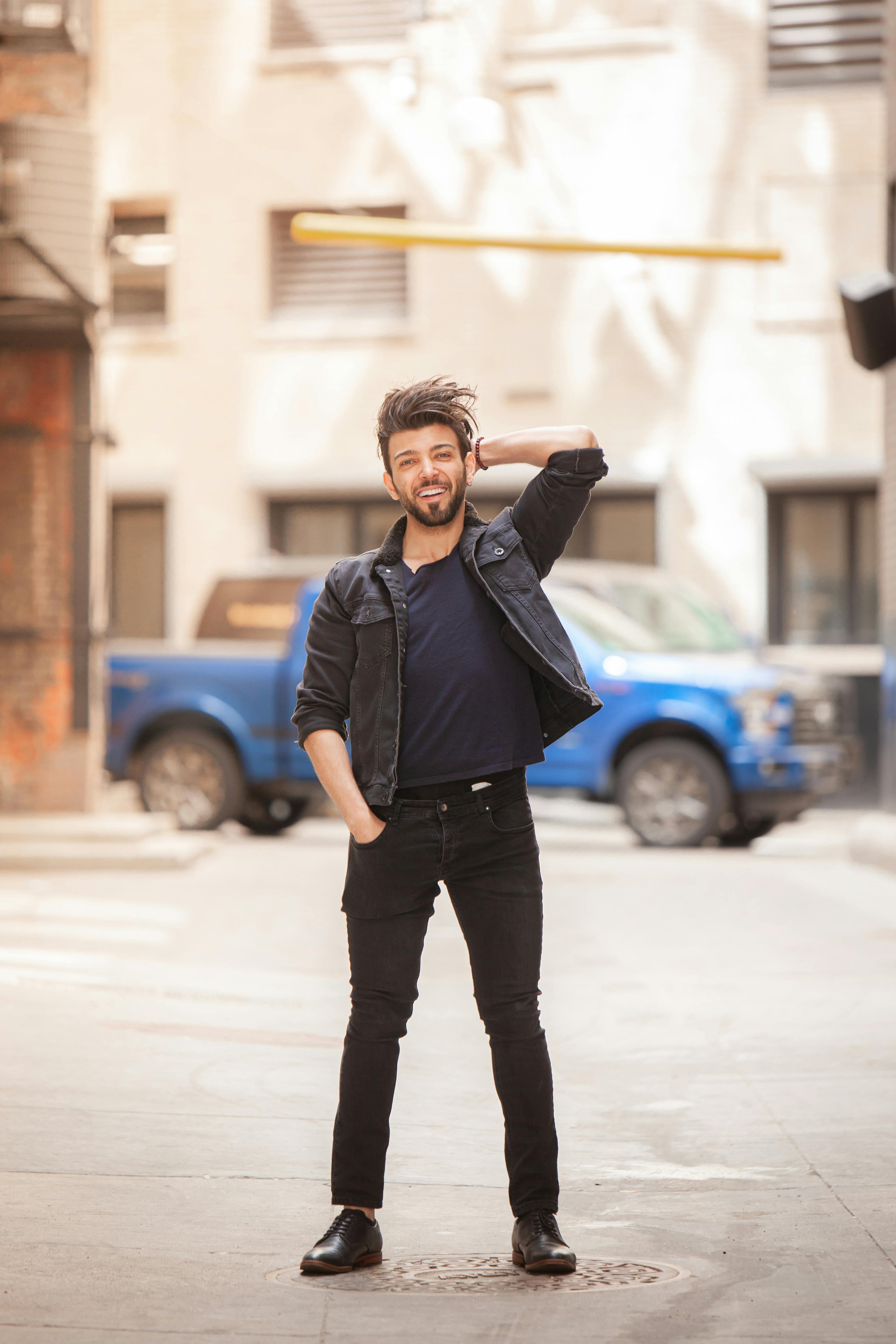Smiling man in casual wear confidently posing in an urban street on a sunny day.