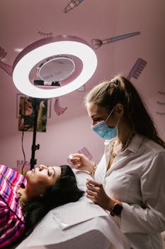 Woman enjoying a relaxing facial treatment at a modern spa salon, under a bright ring light.
