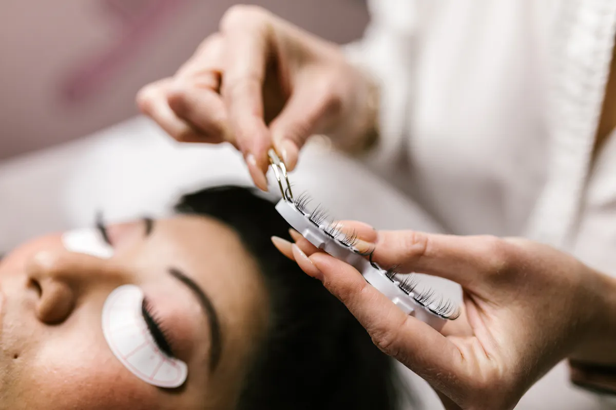 Close-up of a beautician applying false eyelashes to a client, showcasing the precision and care involved in this beauty treatment.