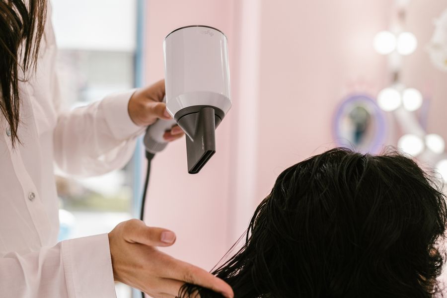 Female stylist blow drying a client's hair