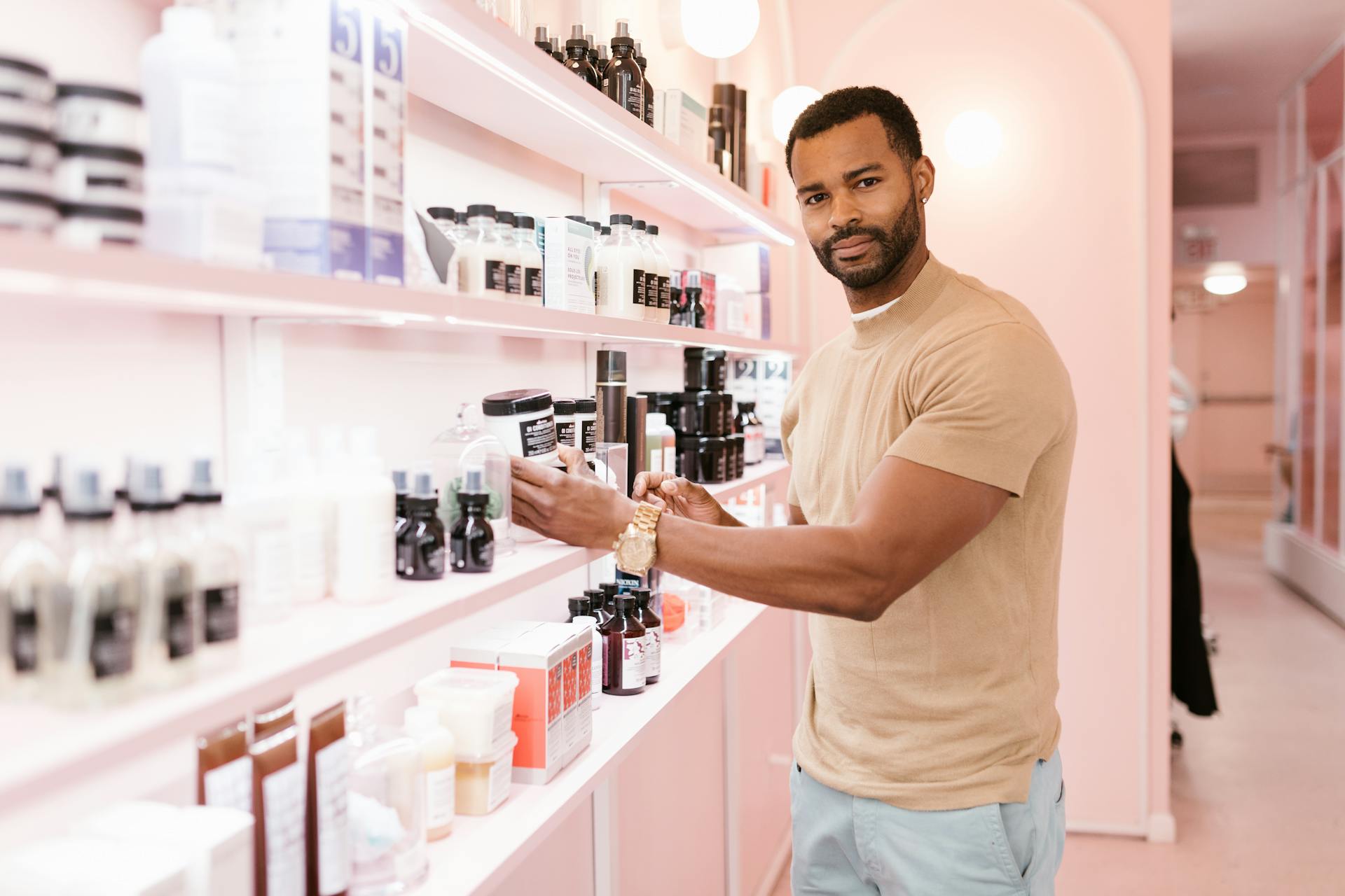 A Man Standing Next to a Shelf with Variety of Beauty Products