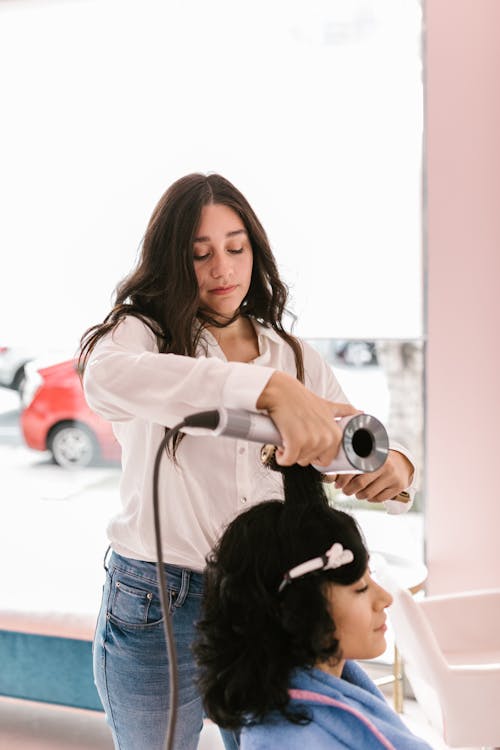 Woman in White Long Sleeve Shirt Using a Hair Dryer on Customer