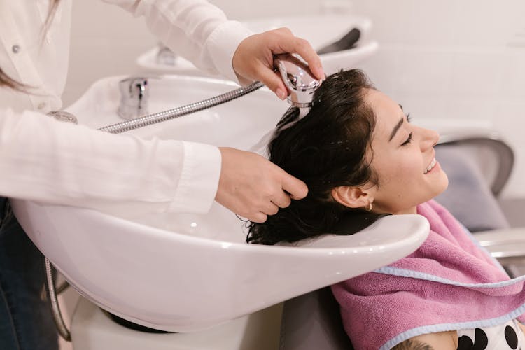 A Person Washing A Woman's Hair In The Salon