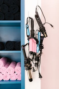 A vibrant display of curling irons on wall hooks next to neatly stacked salon towels.