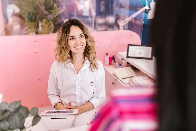 A Female Front Desk Receptionist Smiling To A Client