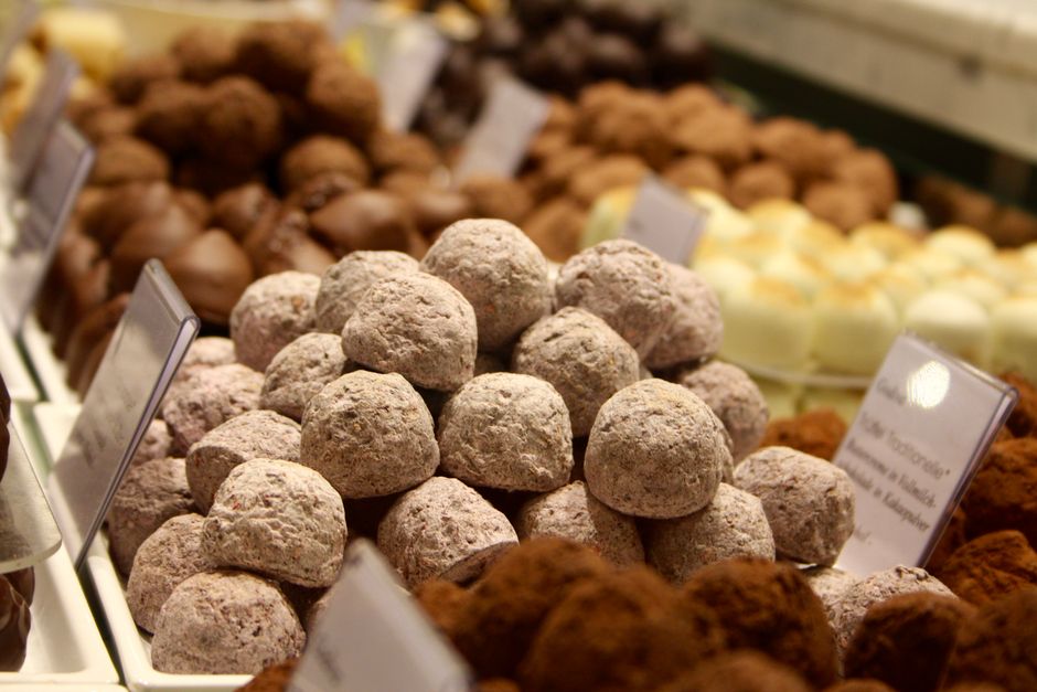 A variety of delicious chocolate truffles on display in a confectionery store with labels.