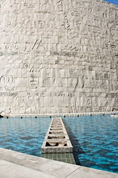 白天的氛围中，石墙、古文字雕刻与水景相映成趣