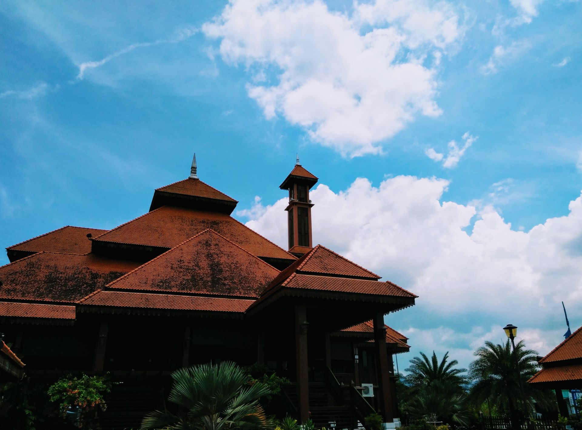 A beautifully crafted traditional building with a striking roof design set against a picturesque blue sky.