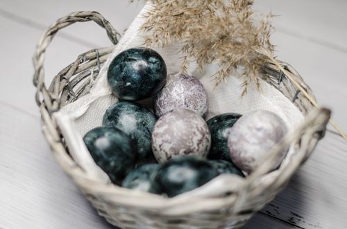 Free A rustic wicker basket filled with nature-inspired decorated eggs and dried foliage. Stock Photo