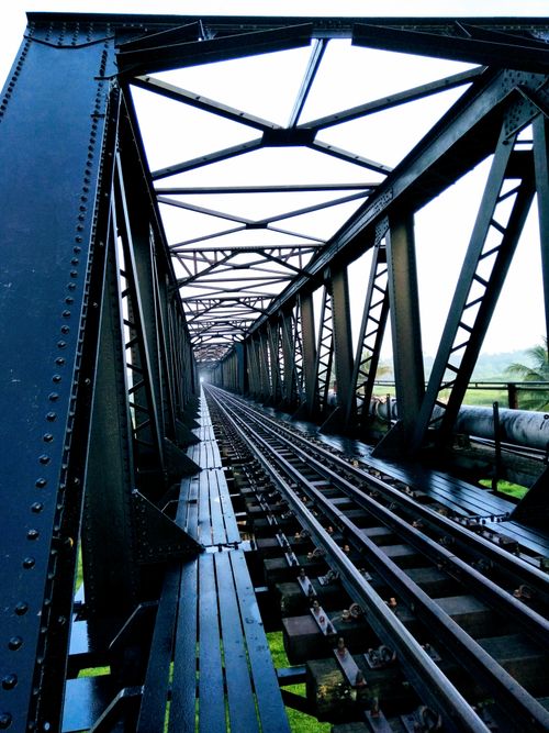 Free A perspective view of a steel railway bridge with intricate ironwork, captured during the day. Stock Photo