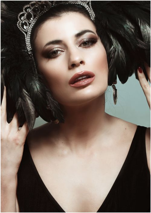 Free A striking portrait of a woman with a feather headdress and elegant jewelry, exuding confidence. Stock Photo