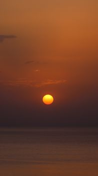 Stunning view of the sunset over a calm ocean with vibrant warm hues in the sky.