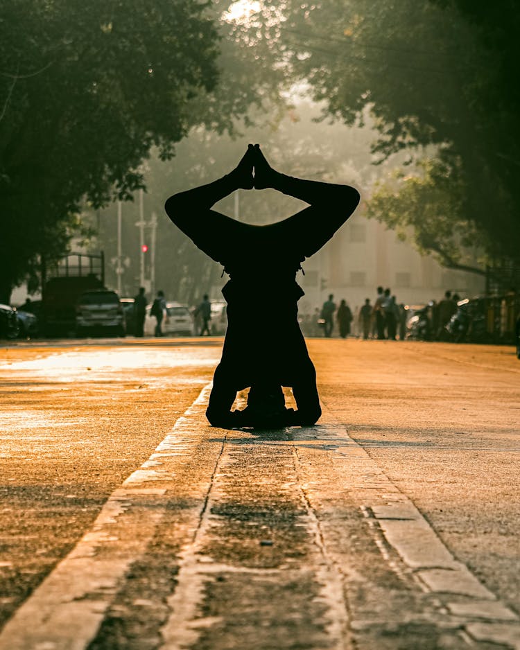 Silhouette Of A Person Doing A Head Stand On A Road