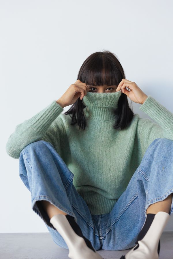 Woman in a kelly green sweater with classic blue denim