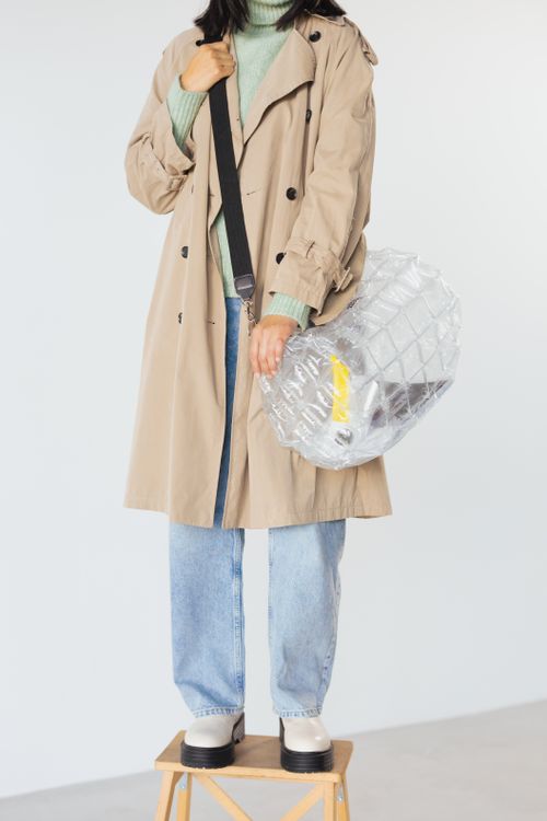 Free Stylish modern look featuring a trench coat and clear bag. Stock Photo