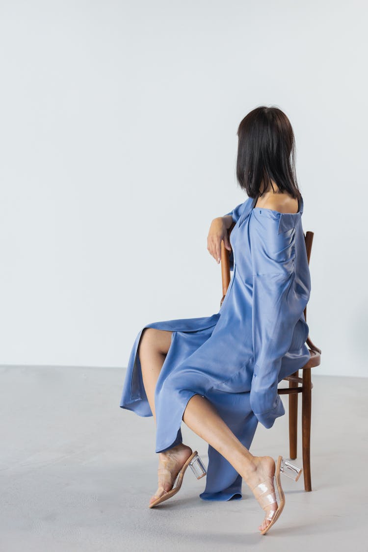 Woman In Blue Dress Sitting On A Wooden Chair