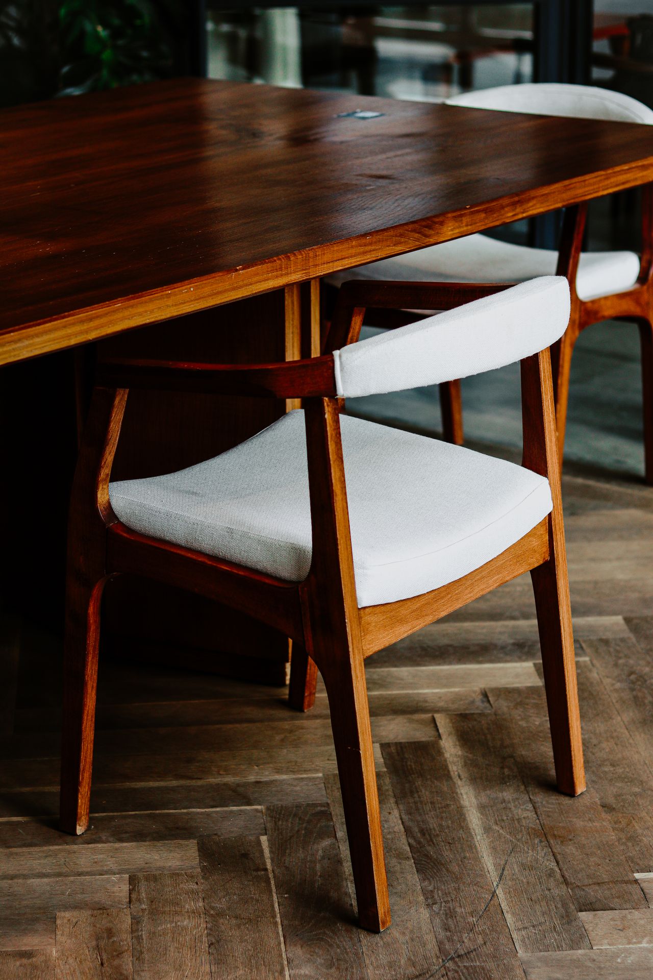 Mid-century wooden armchair with white cushion at a walnut dining table