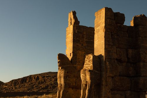 Free Sunlit ancient ruins of Persepolis with intricate stone carvings and clear blue sky. Stock Photo
