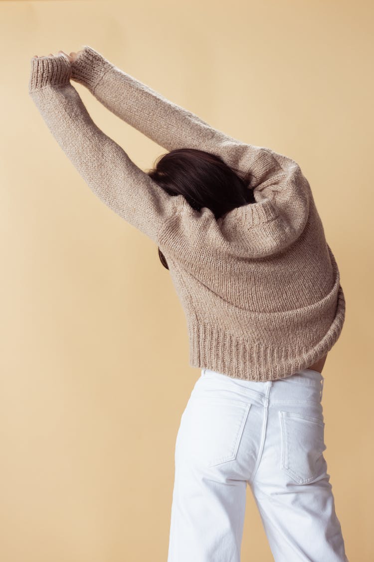 A Woman In Brown Sweater And White Denim Jeans