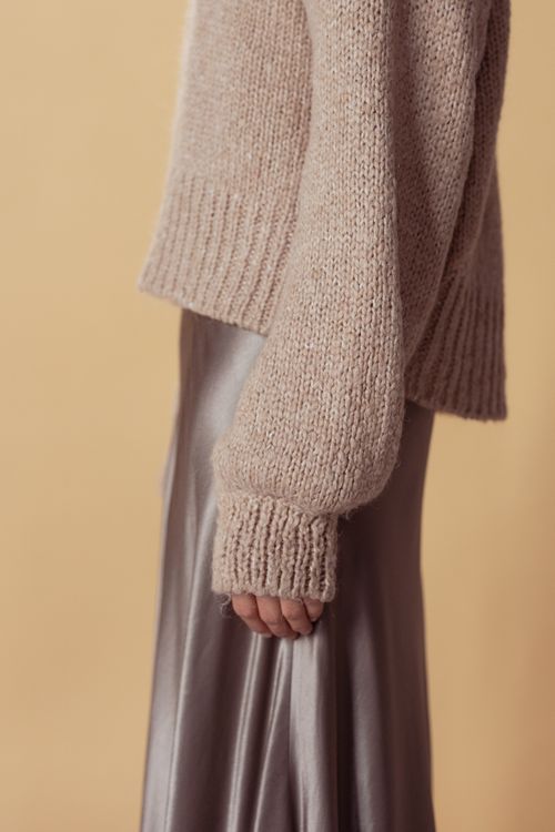Woman wearing a satin slip skirt with a chunky sweater
