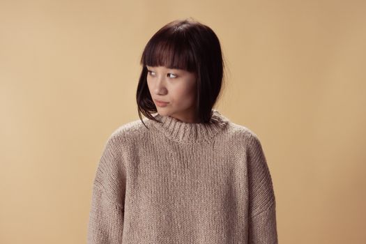 Portrait of a woman in a beige knit sweater set against a warm background.