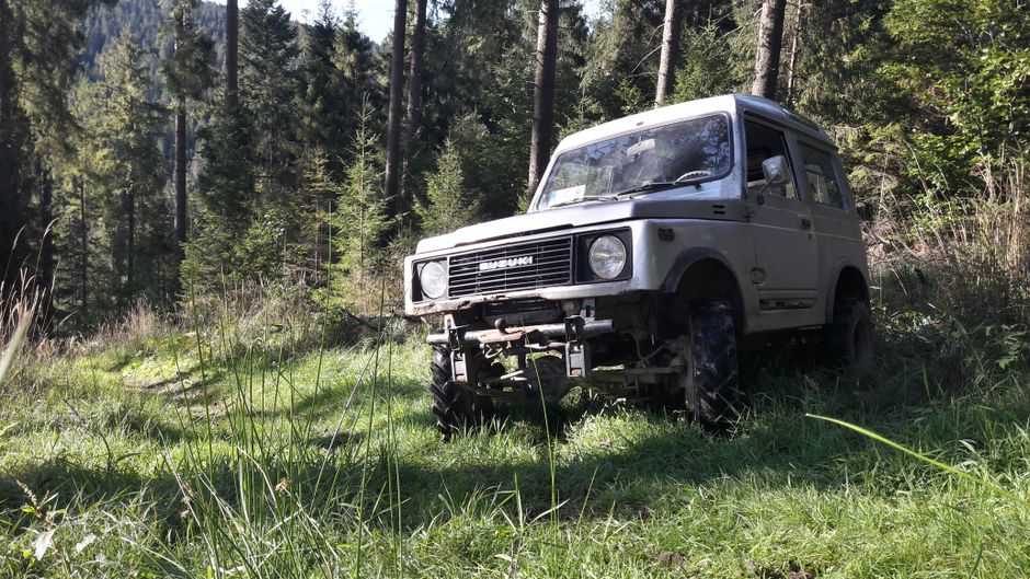A rugged off-road vehicle parked in a lush green forest, ready for adventure.