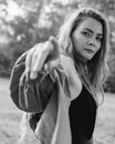 Young stylish woman reaching hand towards camera in park