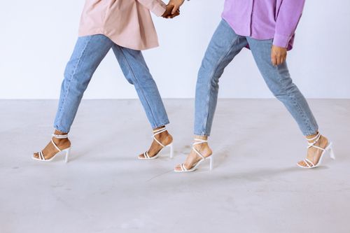 Free Two women walking stylishly in high heels and jeans against a white background. Stock Photo