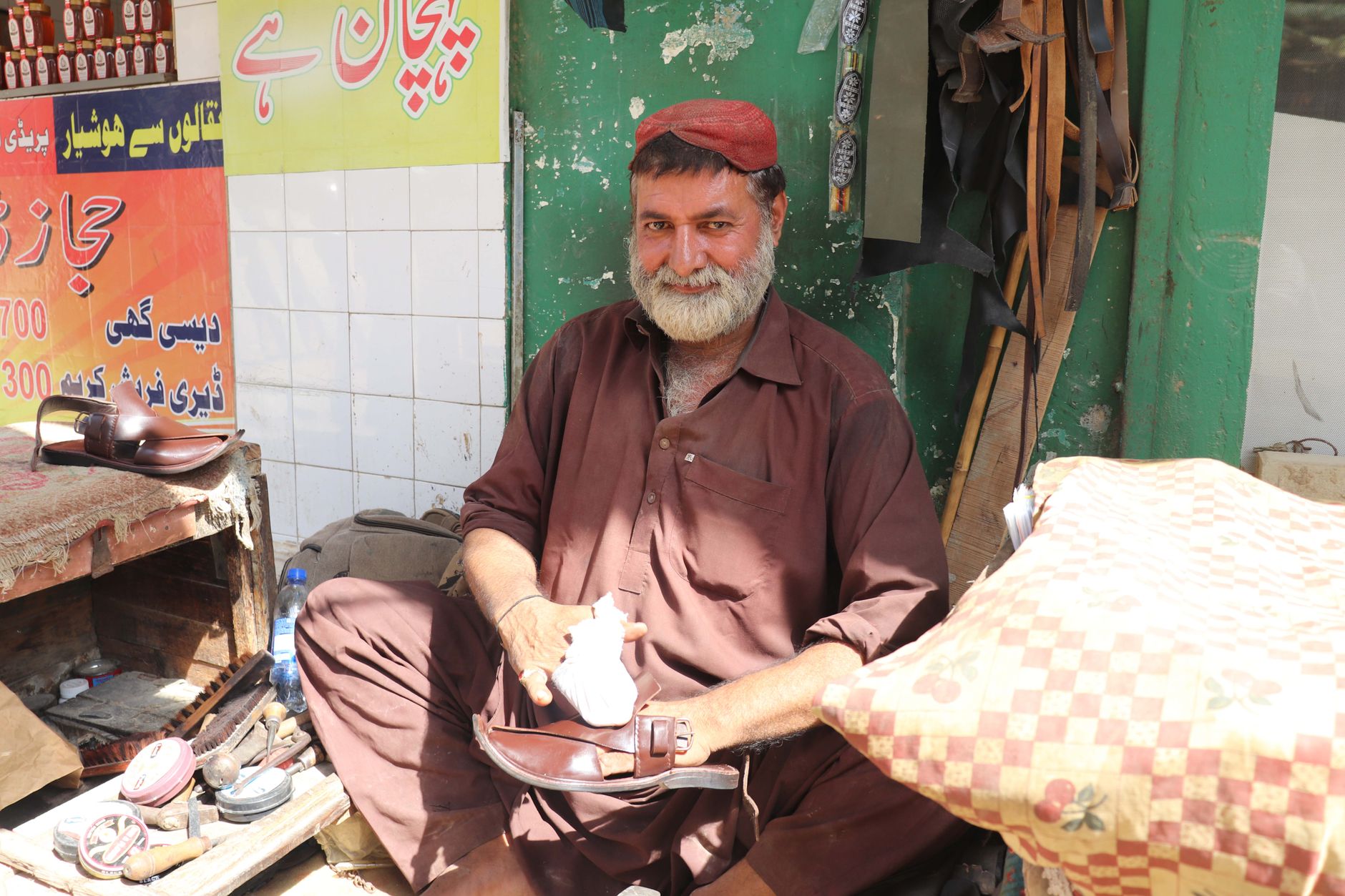 A skilled shoemaker at work in the bustling streets of Karachi, Pakistan.