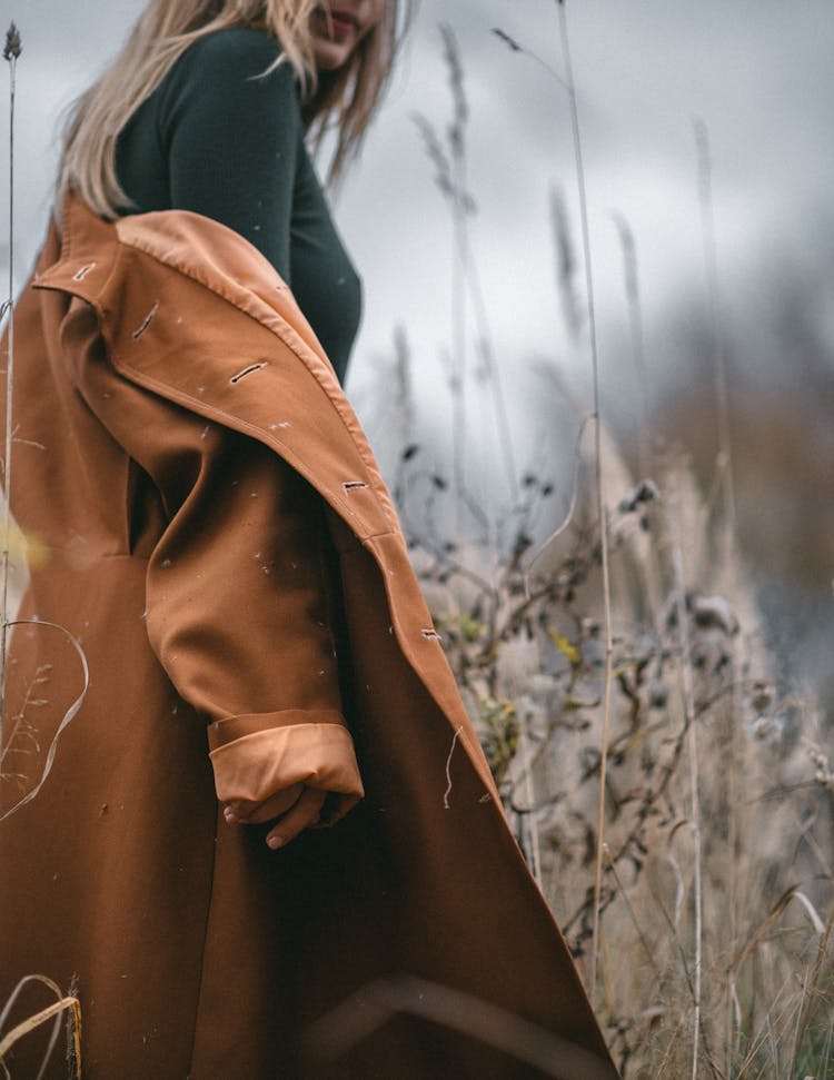 Stylish Woman In Trendy Coat In Field With Dry Grass