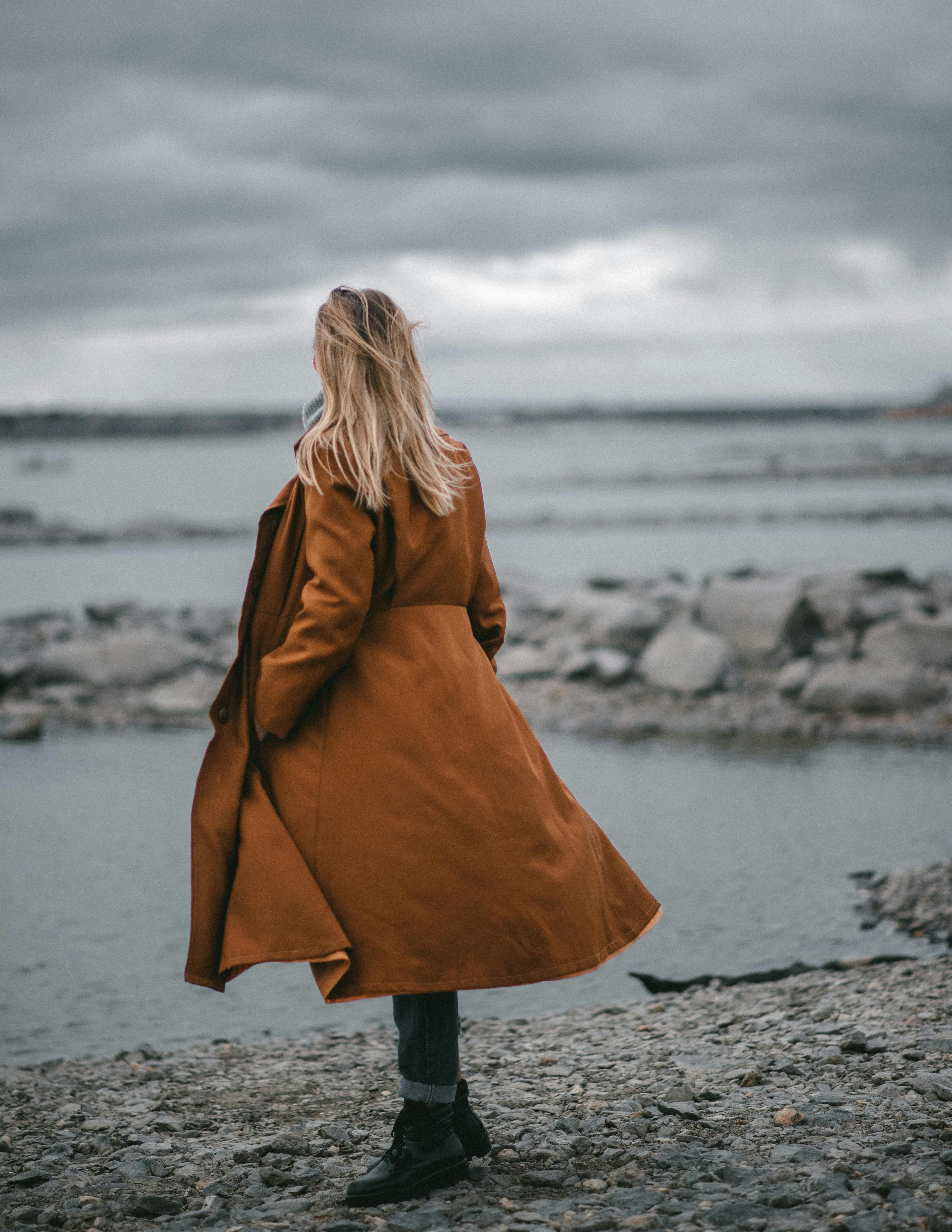 Woman in stylish beige coat admiring endless wavy sea · Free Stock Photo