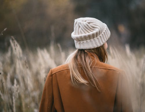 Woman in woolen white hat and warm coat in field