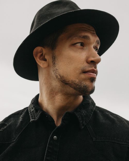 Free Handsome bearded male in black denim shirt wearing trendy headwear and looking into distance on white background in light room Stock Photo