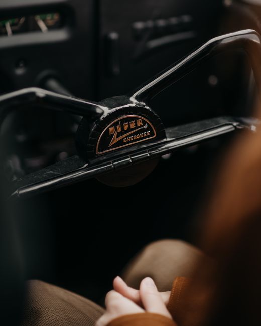 Crop unrecognizable blurred pilot sitting behind black steering wheel in modern aircraft cockpit with dashboard and control panel during flight