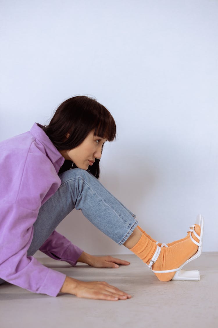 A Woman In Socks And Heels Sitting On The Floor