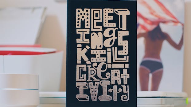 A desk displaying a motivational sign reading 'Meetings Kill Creativity' on a colorful backdrop.