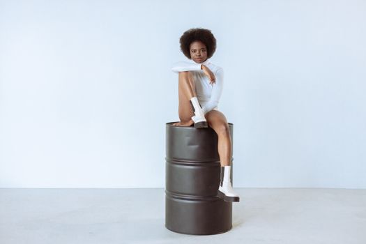 Artistic studio portrait of a woman with afro hair posing elegantly.