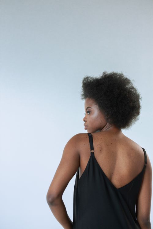 Free Fashion portrait of an African American woman with afro hair wearing a stylish black dress in a studio setting. Stock Photo