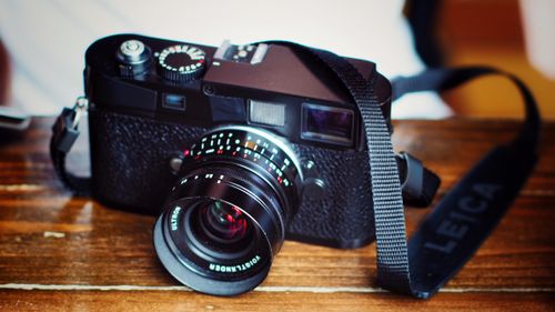 Free Close-up of a vintage classic camera placed on a textured wooden table with focus on lens. Stock Photo