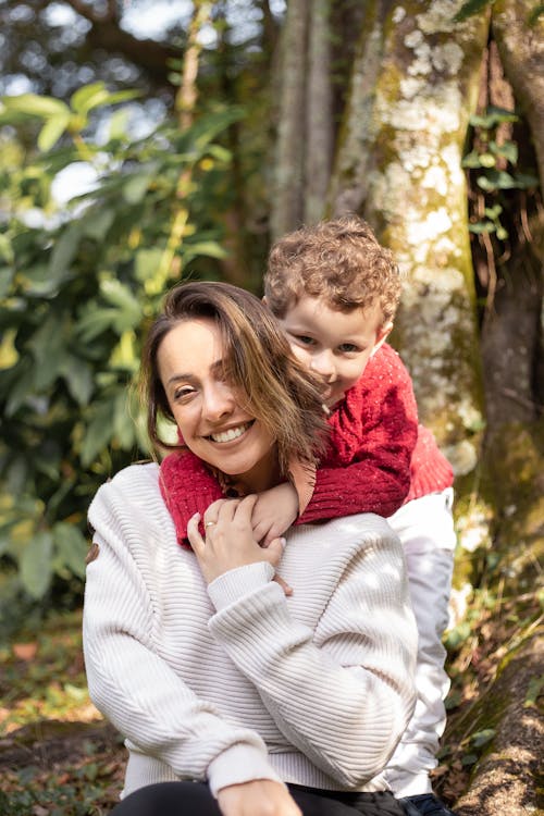 Photo of a Boy in a Red Knit Sweater Hugging Her Mother