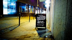 在鹅卵石街道上，晚上制作啤酒标牌，捕捉城市氛围