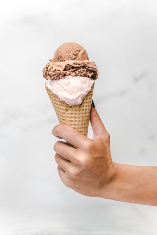 Close-Up Photo of a Person's Hand Holding a Delicious Ice Cream
