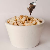 Tub of swirled gelato with a spoon of chocolate sauce, photo by Nick Mayer on Pexels