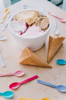 A vibrant display of multi-flavor ice cream with waffle cones and colorful spoons.