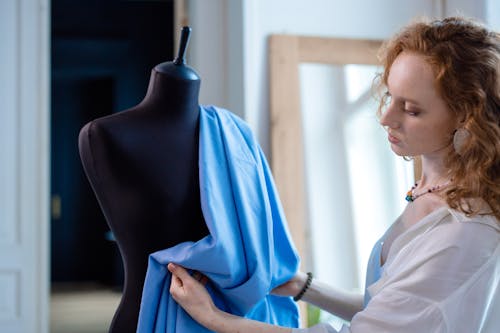 Woman in White Blouse Putting the Blue Fabric on the Mannequin